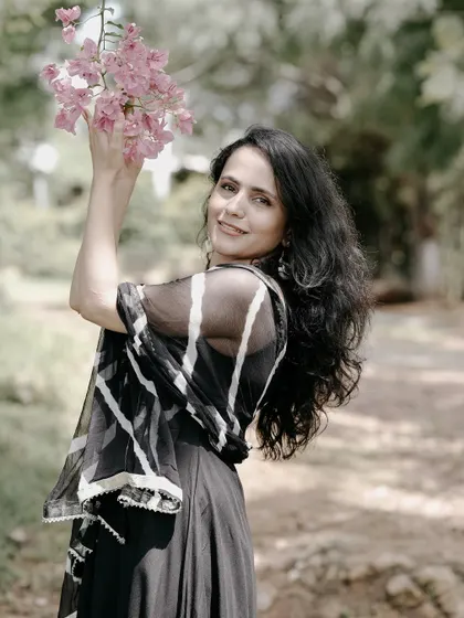 A beautiful solo portrait of the bride-to-be, smiling as she holds a branch of pink bougainvillea.