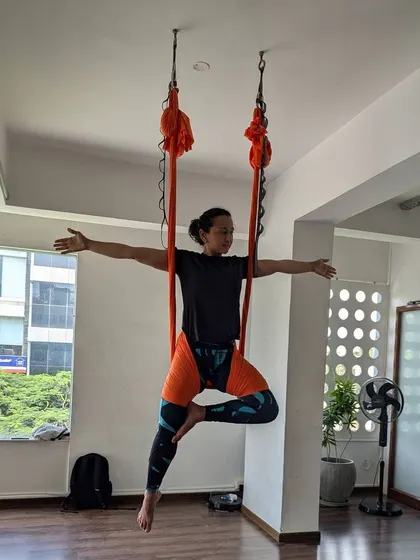 A student gracefully holds a pose, demonstrating the balance and core strength developed through consistent aerial yoga practice.