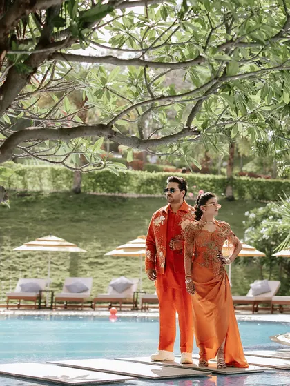 The couple posing by the pool, their coordinated outfits and the resort backdrop creating a picture of relaxed luxury.