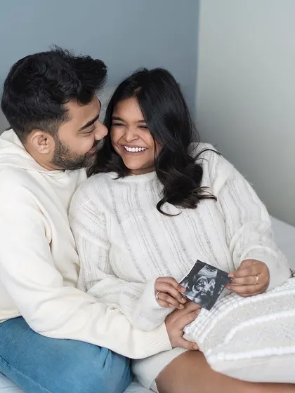 Sharing a smile over their baby's first picture. This cozy, at-home style shot captures the excitement of seeing the ultrasound and dreaming of the future.