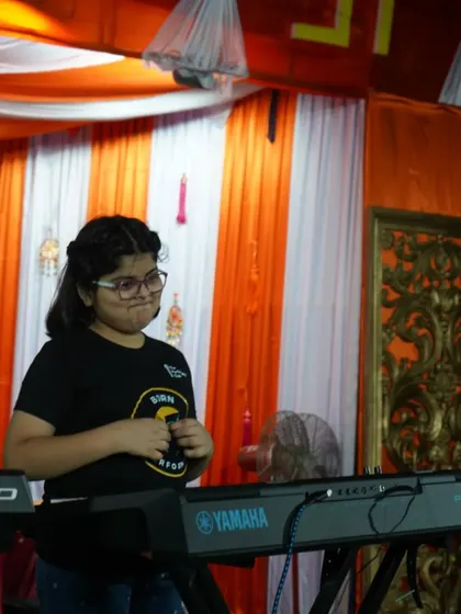 **Confidence on Stage.** A young performer at her keyboard, ready for her turn to play. We don't just teach notes; we build the confidence to perform in front of an audience.