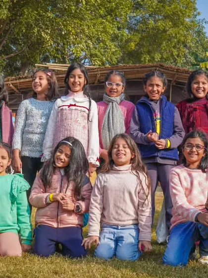 A group of young girls smiling and posing for a group photo on the lawn.