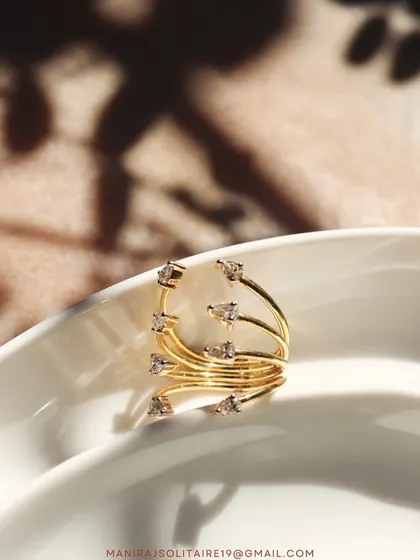 This swirling gold ring is designed to wrap elegantly around the finger. It's adorned with scattered diamonds that catch the light beautifully, making it a perfect piece for someone who loves delicate, nature-inspired designs.