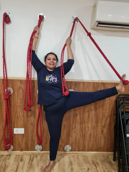 This student finds confidence in her standing split with the help of the wall ropes. This is a great example of how we build strength and flexibility progressively.