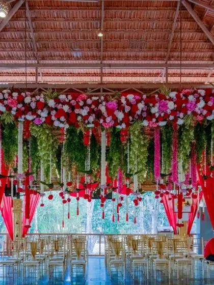 The ambiance of a wedding is essential. Here is an example of our floral decor at the Mahalaxmi Mantap, where cascades of red and white flowers create a breathtaking and sacred space for the ceremony, reflecting a blend of natural beauty and traditional elegance.