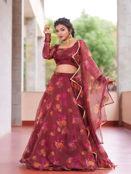 A model in a beautiful maroon organza lehenga with a vibrant floral print, perfect for a sangeet or mehendi.