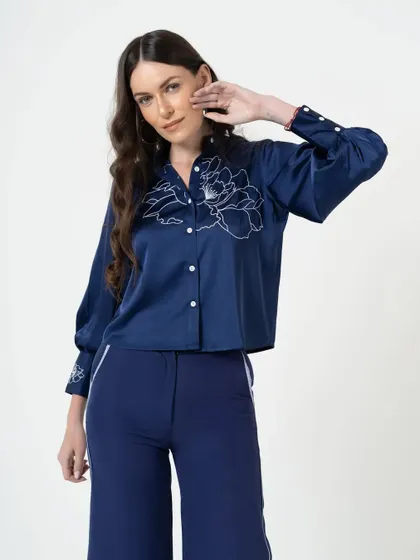 A close-up portrait from the campaign, highlighting the embroidered details on the shirt. Detail shots are essential for communicating product quality.