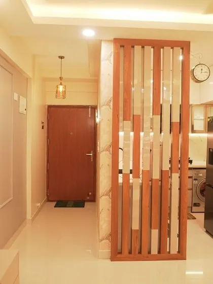 An open-plan living area featuring a wooden partition with marble-finish inlays that separates the entryway from the main living space. The design is both functional and aesthetically pleasing.