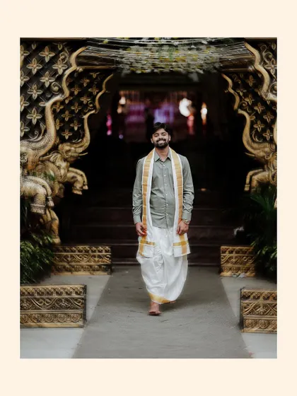 A cool, confident portrait of the groom walking through the ornate temple-like doorway.