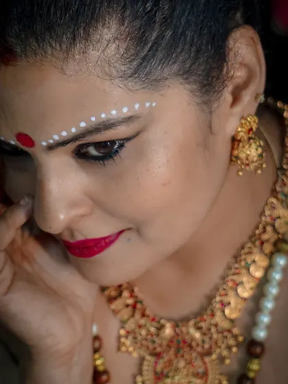 A detailed shot of the traditional makeup for the Onam look, with a red bindi and white sandalwood paste design on the forehead.