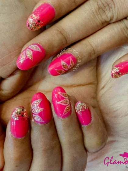 A vibrant and festive design. We used a hot pink base and added gold glitter tips, with accent nails featuring a beautiful, hand-painted leaf design in gold.