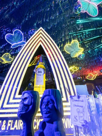 The bar setup for the neon-themed cocktail party, featuring quirky glasses and a custom-branded backdrop.