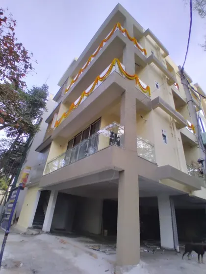 A low-angle view of a building decorated with simple flower garlands for a home ceremony.