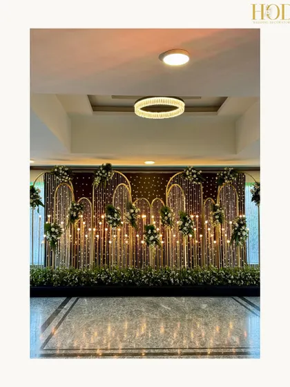 A stunning photo booth backdrop made of golden arches, fairy lights, and floral accents, creating a perfect spot for glamorous photos.