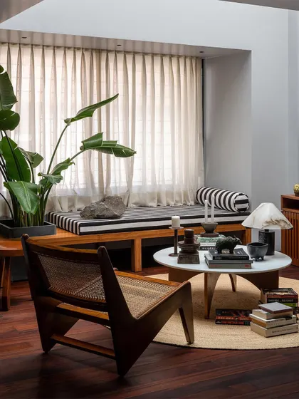 The lounge is styled with personal objects, books, and comfortable furniture like this classic wooden armchair. I believe in creating spaces that are not just beautiful, but also deeply personal and livable.