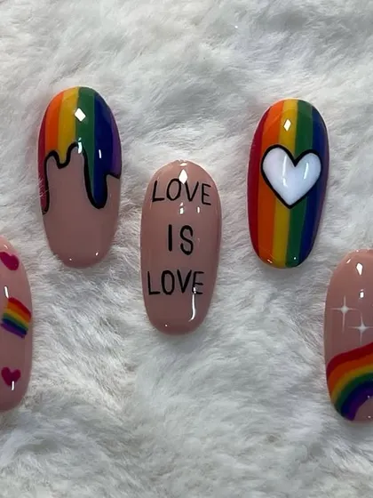 "Love is Love." A set of nails created for Pride Month, featuring rainbows, hearts, and a powerful message.