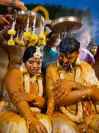 The couple gets showered with water and flowers during a fun-filled Haldi ritual, a moment of pure celebration and joy.