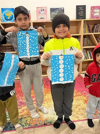 Happy faces from our winter camp! The children are proudly holding up the snowman name crafts they made.