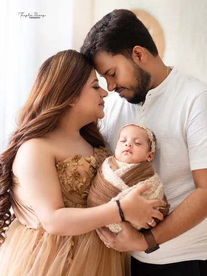 An intimate portrait of a new family of three. The soft lighting and close embrace create a feeling of warmth and security.