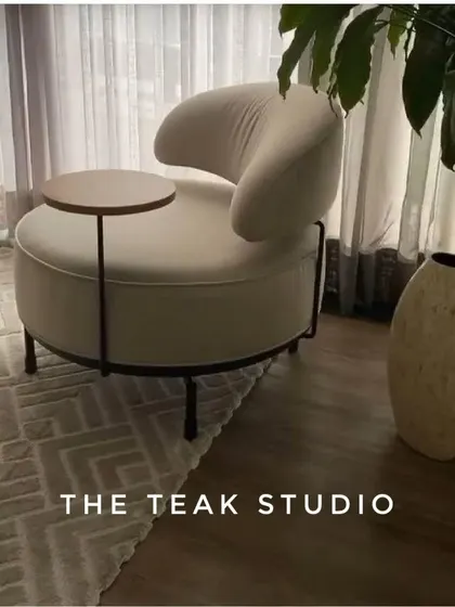 A highly functional and stylish accent chair. This piece features a comfortable, rounded design with an attached swivel table, making it the perfect chair for a reading nook or a compact living area where you need a surface for a drink or a book.