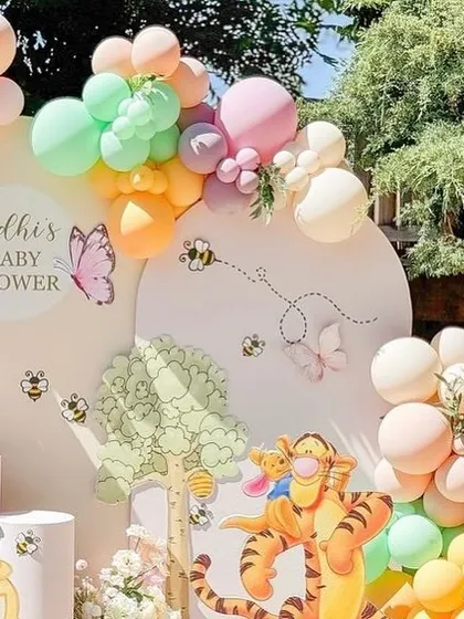 A wide view of the pastel-colored Winnie the Pooh baby shower, perfect for an outdoor event with natural lighting.