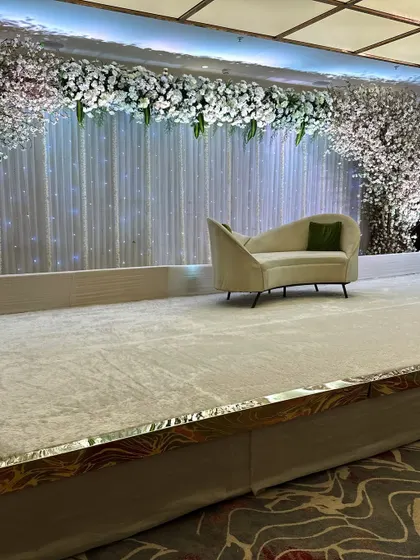 For a winter wedding, we created this chic and minimalist stage. A simple white floral arch and cherry blossom trees against a sparkling white backdrop give it a clean and magical feel.