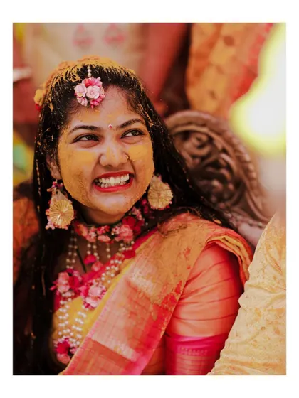A close-up of the bride's joyful, gritted-teeth smile during her Haldi, a moment of pure, uninhibited fun.