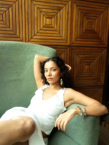 A relaxed and confident portrait in an armchair. The wooden paneling in the background adds warmth and texture.