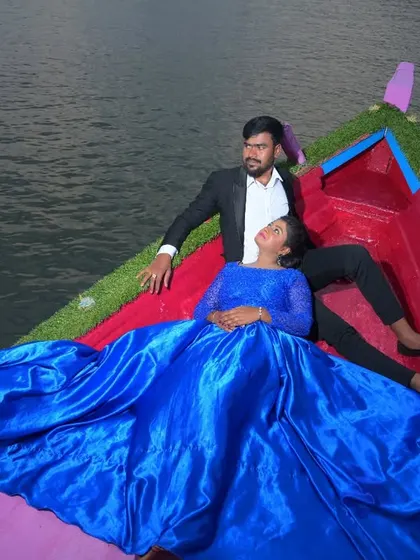 A unique and artistic pre-wedding photo of a couple relaxing in a boat. The vibrant blue of the satin gown creates a stunning contrast with the water.
