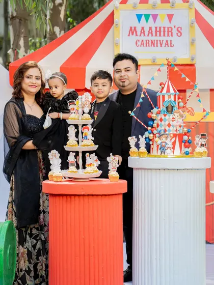 A portrait of the happy family at their carnival-themed birthday party. The detailed cake and colorful backdrop create a festive and joyful atmosphere.