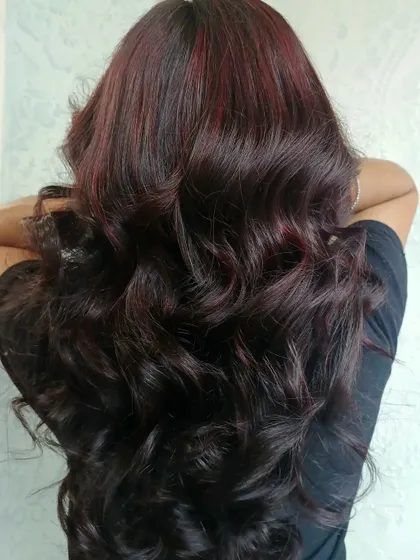 Sometimes you just need to paint it red. This look features subtle red highlights woven into very dark, long hair, creating a peekaboo effect that adds a touch of drama and sophistication.