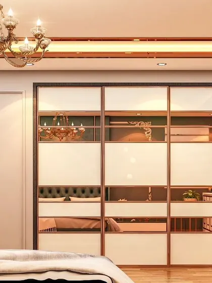 This sliding wardrobe features a modern design with alternating panels of white and rose-gold mirror. The reflective surfaces make the room feel larger, while the copper-toned ceiling adds a warm, luxurious glow.