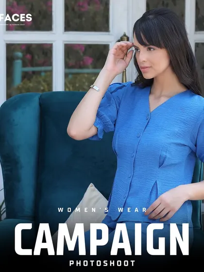 A model in a stylish blue top seated in a velvet armchair, creating a sophisticated and relaxed campaign image for a women's wear brand.