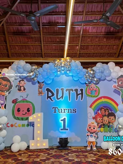 A Cocomelon first birthday party under a gazebo. This setup features a full character backdrop, light-up number '1', and balloon columns in blue, white, and silver.
