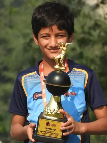 A young player proudly holding his runner-up trophy from the Croire Youth Cup. These moments inspire them to work even harder.