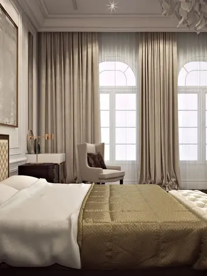 A luxurious bedroom featuring a quilted leather headboard and elegant neutral tones, with large windows providing ample natural light.