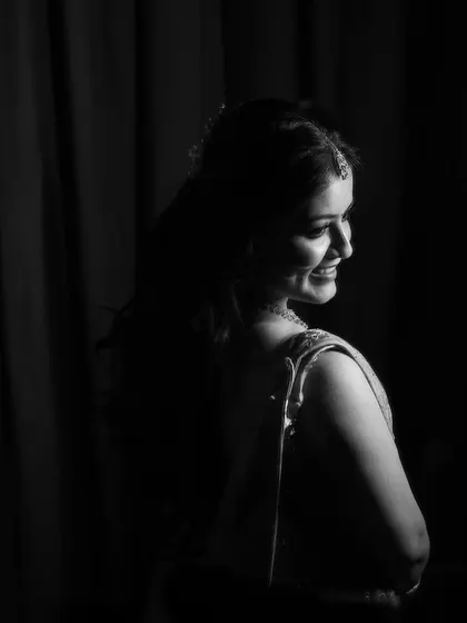 A classic black and white portrait of the bride looking over her shoulder with a gentle smile. The dramatic lighting creates a timeless and elegant image that highlights her happiness.