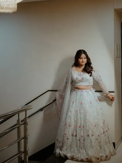 A full-length shot of the bride on a staircase, showing off her elegant engagement lehenga.