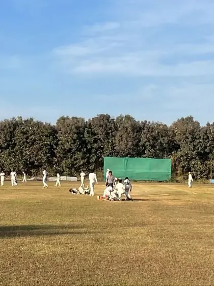A wide shot of a competitive youth cricket match in progress on a sunny day, showing our players in their element.