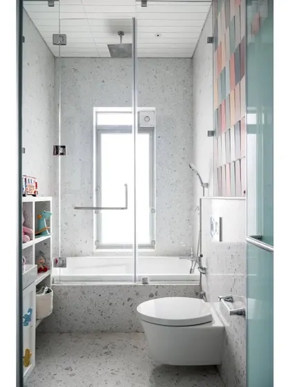 A full view of the baby's bathroom, showing the bright, light-filled space with its terrazzo-style finish and a combination tub and shower.