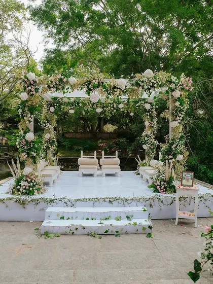 A pristine white mandap at the Pond Pavilion, decorated with lush greenery and white florals for a fresh, organic wedding theme.