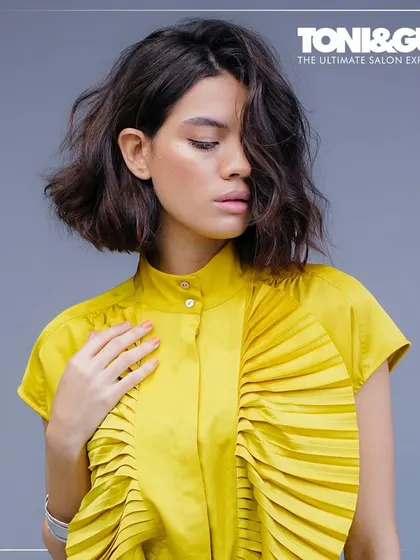 A forward graduation bob with soft, textured waves. This cut is elevated to accentuate the cheekbones, with artful layering that creates dimensional brilliance and fluid movement, a hallmark of modern elegance.