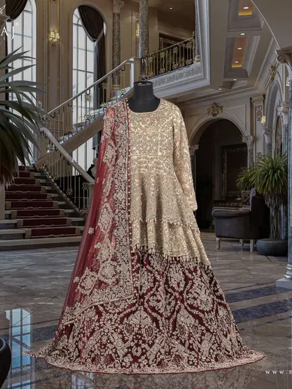 A side view of the gold double-layered peplum top and reddish maroon tail lehenga, highlighting its intricate antique designs.