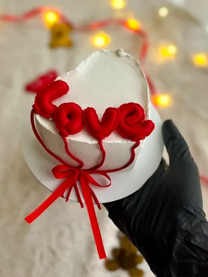 A heart-shaped Valentine's cake with "LOVE" spelled out in balloon-style letters. A sweet and trendy gift for your special someone.