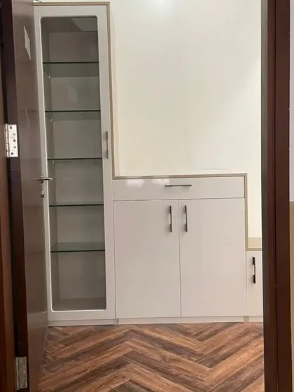 A tall, slim crockery unit with a glass door, designed to fit perfectly in a narrow space while offering ample vertical storage for dinnerware.
