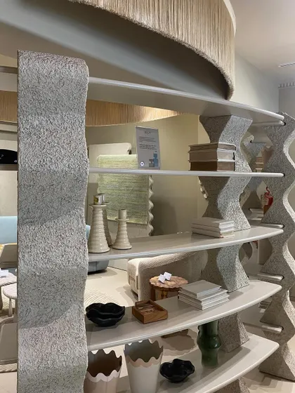 A closer look at the bespoke shelving reveals a textured, stone-like finish that contrasts with the smooth surfaces of the displayed objects. The undulating form of the supports adds a sense of movement and artistry to the functional display unit.