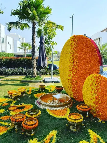 A grand outdoor Haldi setup with large circular marigold structures. The entire lawn is transformed into a field of flowers for a truly immersive experience.