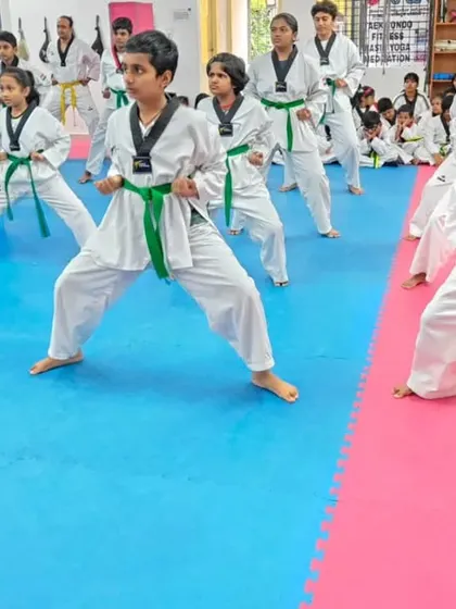 A class of green belts practicing their stances with focus.