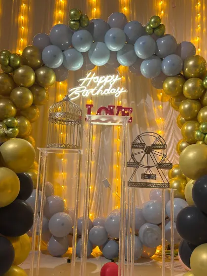 This birthday setup uses a sophisticated color palette of grey, gold, and black balloons. I've included decorative props like a birdcage and a mini Ferris wheel to add unique touches.