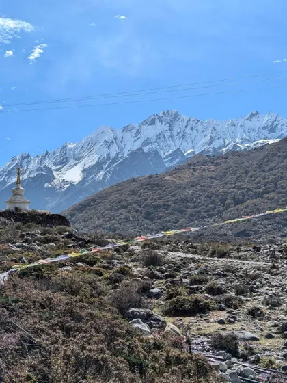 Prayer flags stretch across the landscape with the majestic Langtang Lirung peak in the background, a constant reminder of the region's spiritual significance.